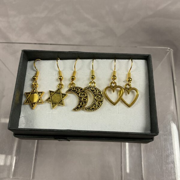 Close-up of 925 silver gilt earrings set with star, moon, and heart designs.