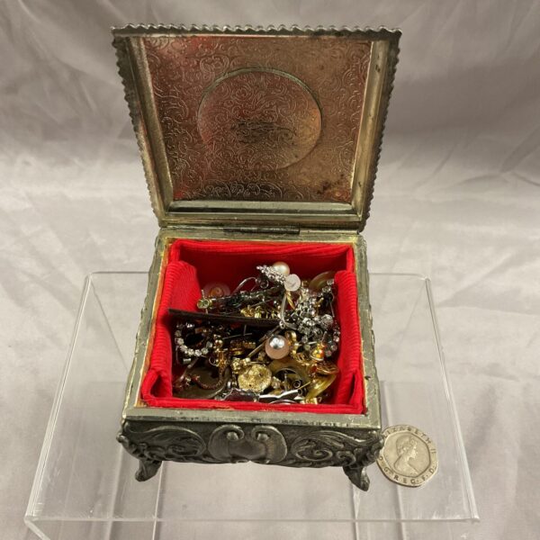Front view of a vintage cameo jewellery box filled with earrings.
