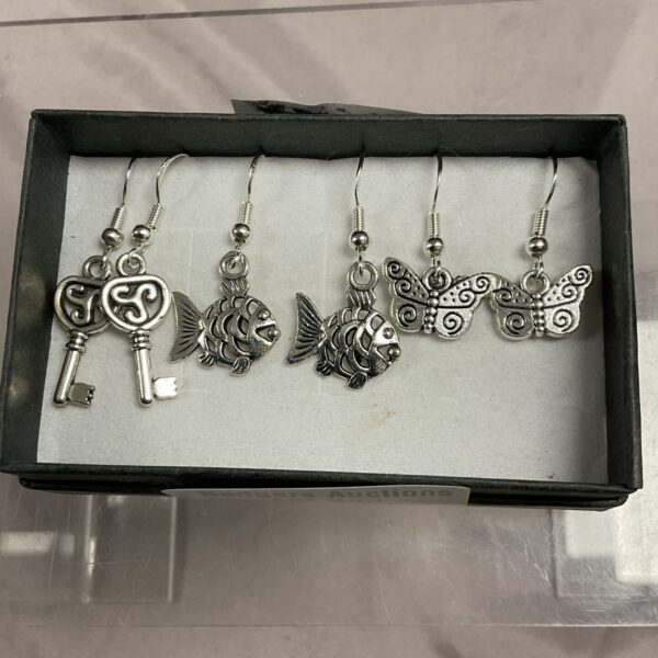 Close-up of 925 silver earrings featuring fish, key, and butterfly designs.