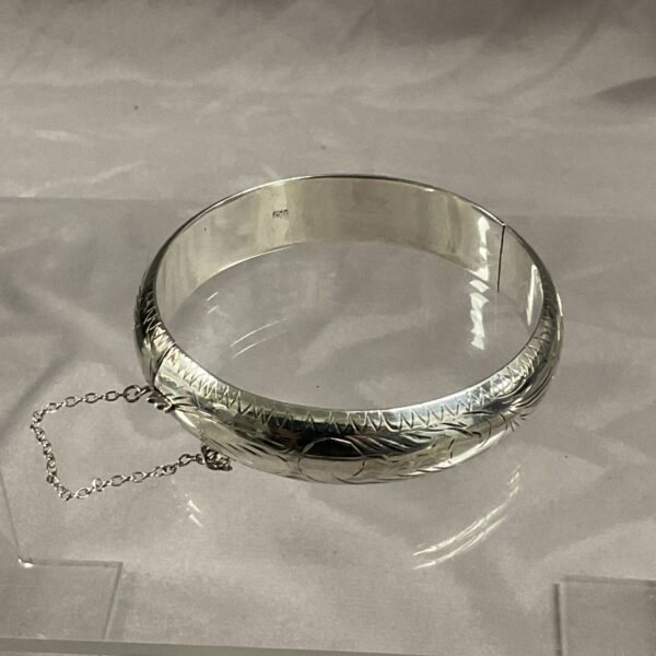 Vintage silver hinged bracelet with embossed floral design.