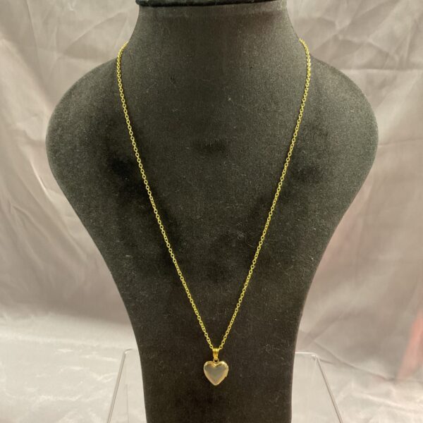 Close-up of silver gilt heart locket necklace on a neutral background.