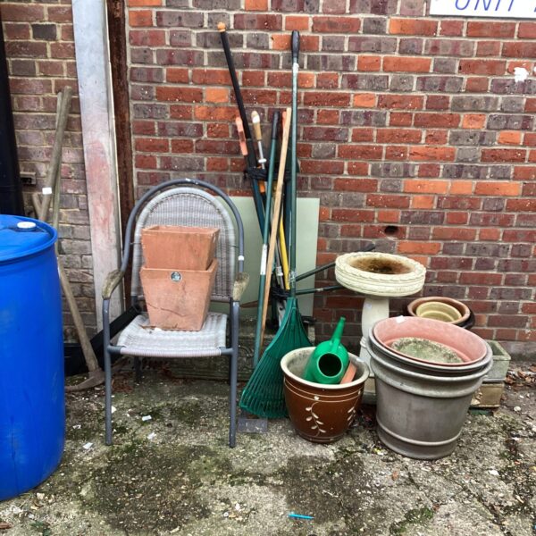 Mixed lot of garden planters, tools, and furniture for outdoor use.
