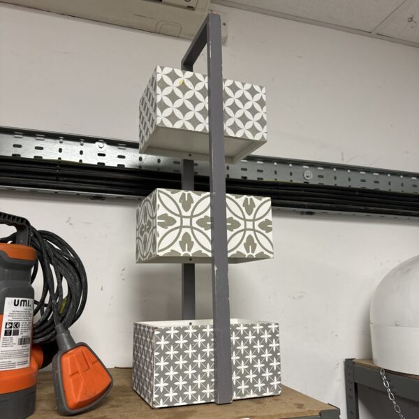 White and grey geometric tiered wooden shelf unit for display.