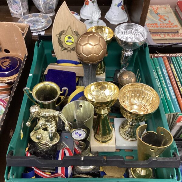 Collection of vintage football trophies and medals on display.