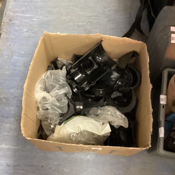 Box of assorted plastic guttering fittings for rainwater drainage.