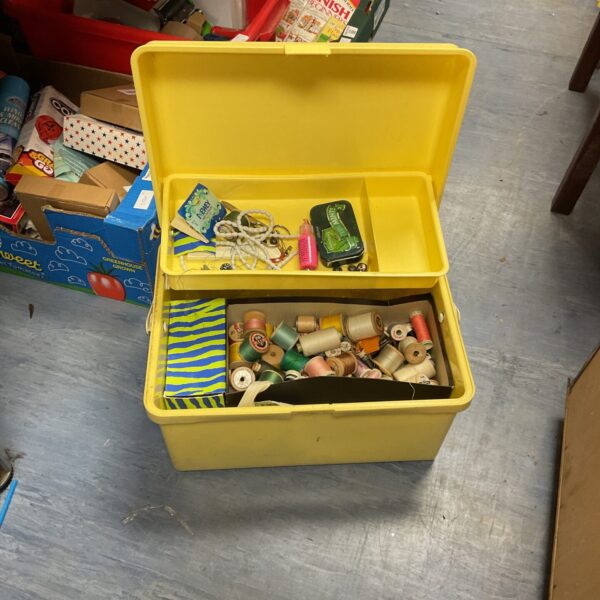 Yellow plastic box filled with a colourful sewing and craft lot.