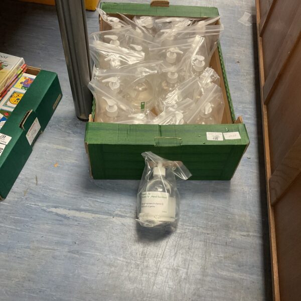 Bulk lot of hand sanitizer bottles in a green crate.