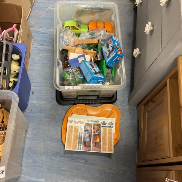 Clear storage box filled with a large Playmobile toy lot.