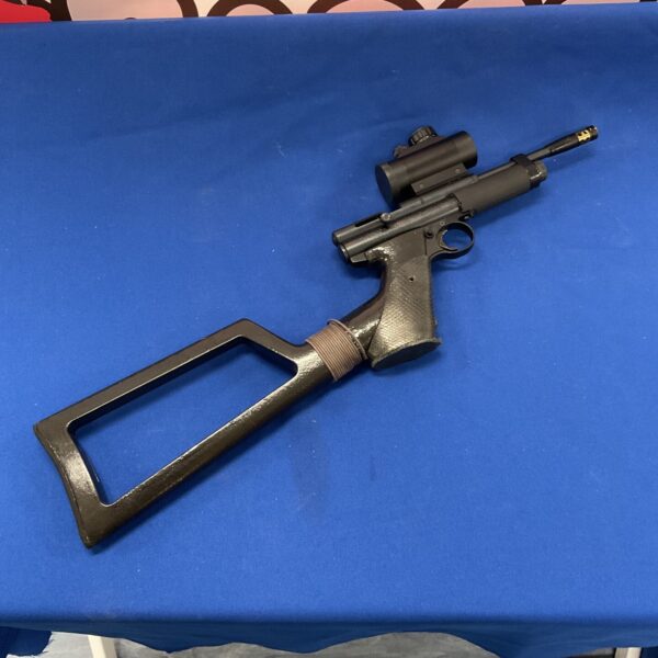 Dark Crossman 2240 air pistol with stock and scope on blue backdrop.