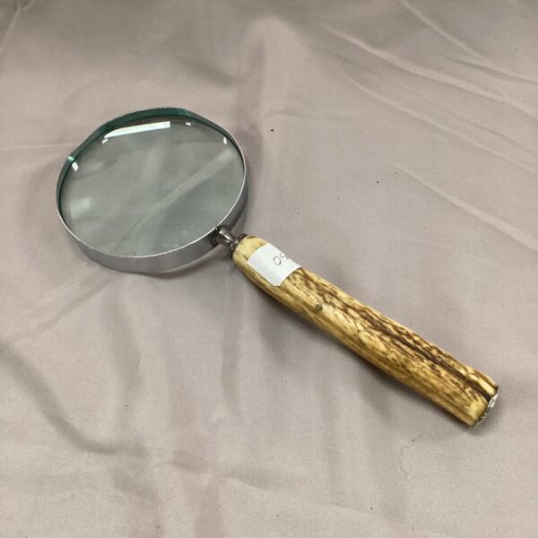 Vintage magnifying glass with a detailed bone handle.
