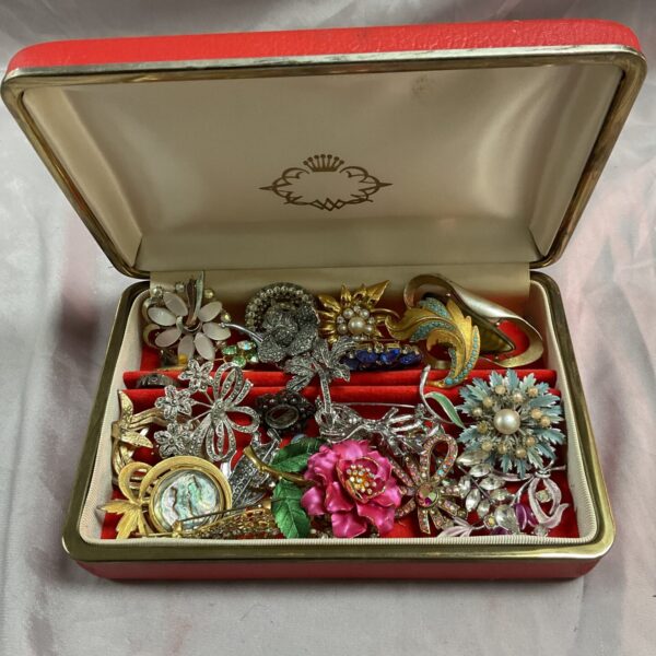 Vintage brooch assortment displayed inside a red jewellery box.