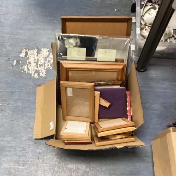 Assorted vintage and empty picture frames in a cardboard box.