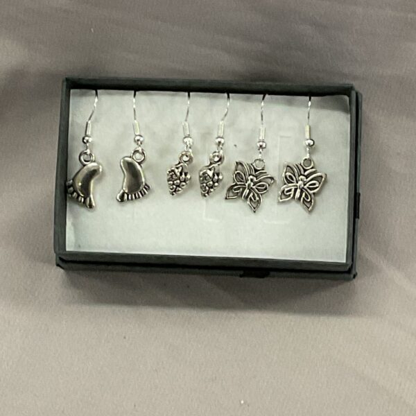 Close-up of three pairs of 925 silver floral dangle earrings.