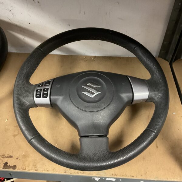 Grey and black Suzuki steering wheel with integrated controls.