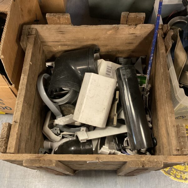 Wooden crate filled with assorted plumbing fittings and pipe connectors.
