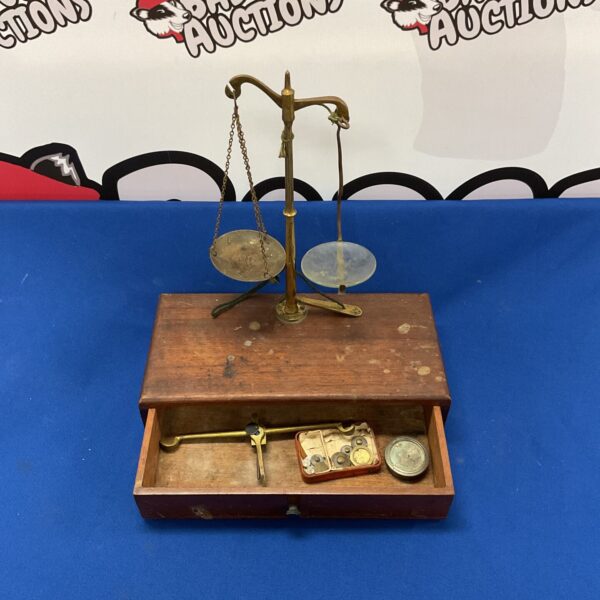 Vintage brass balance scales with weights on a wooden base.