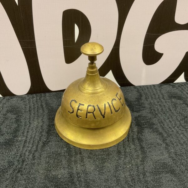 Vintage brass service bell on a dark surface.