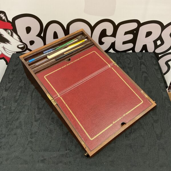 Open Remy Martin Cognac writing slope with vintage pens and stationery.