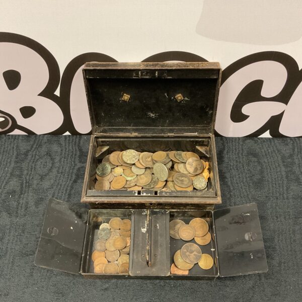 Vintage cash tin filled with mixed coins, antique money box.