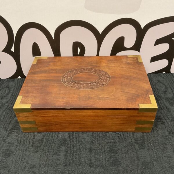 Front view of a vintage wooden jewellery box with brass details.