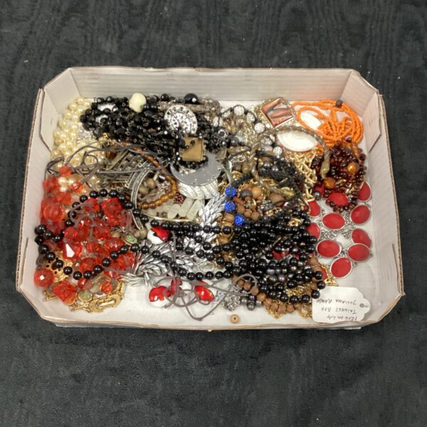 Tray of colourful vintage and costume jewellery pieces.
