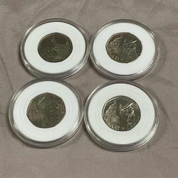 Four Paddington Bear 50p coins in protective capsules.