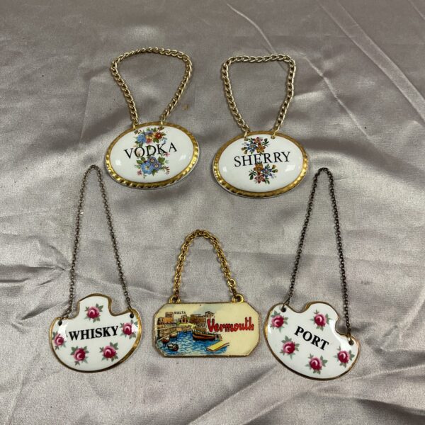 Vintage ceramic and enamel bottle labels for spirits.