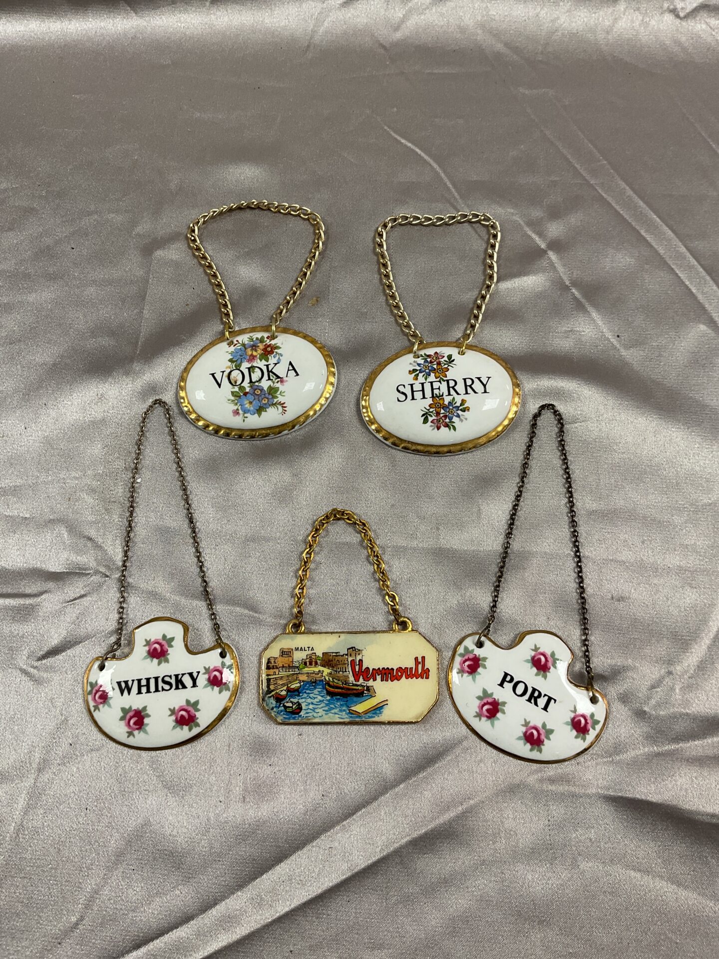 776 Four vintage ceramic bottle labels and one metal enamel label