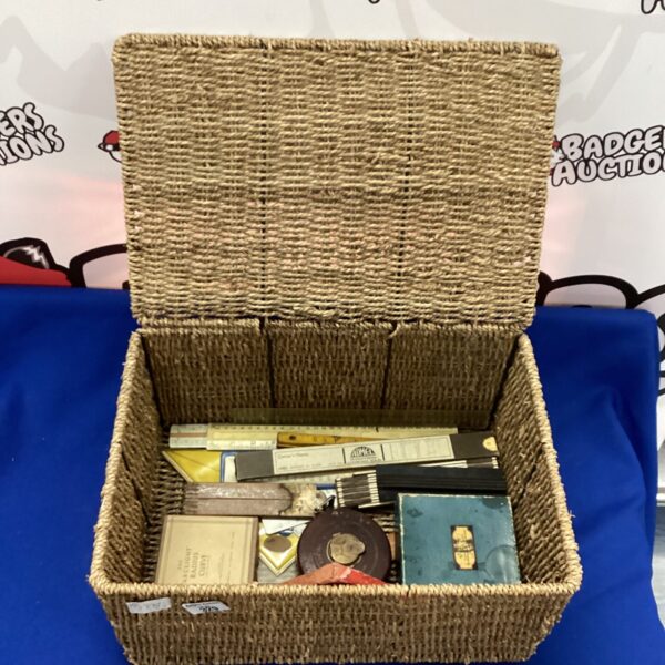 Wicker basket filled with vintage drawing equipment and scale rulers.
