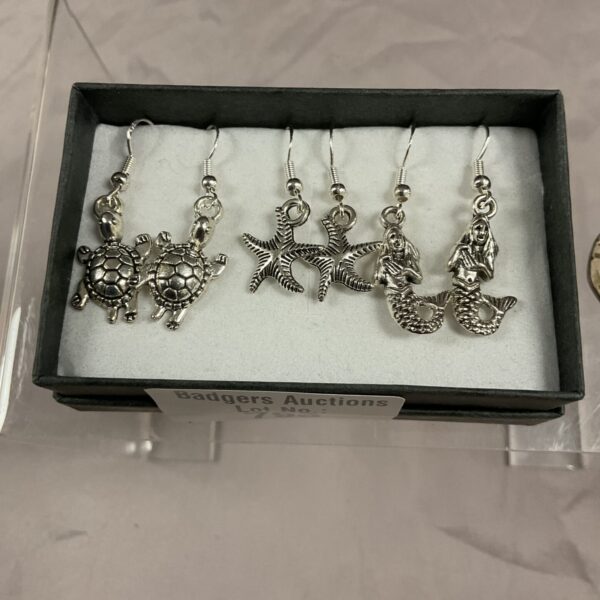 Close-up of 925 silver earrings featuring starfish, turtle, and seahorse designs.