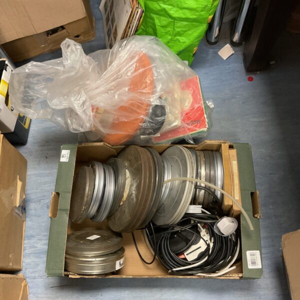 Vintage projector film reels and cans in a tray.