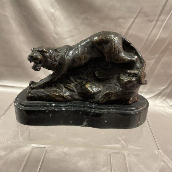 Side view of vintage bronze tiger sculpture on marble base.