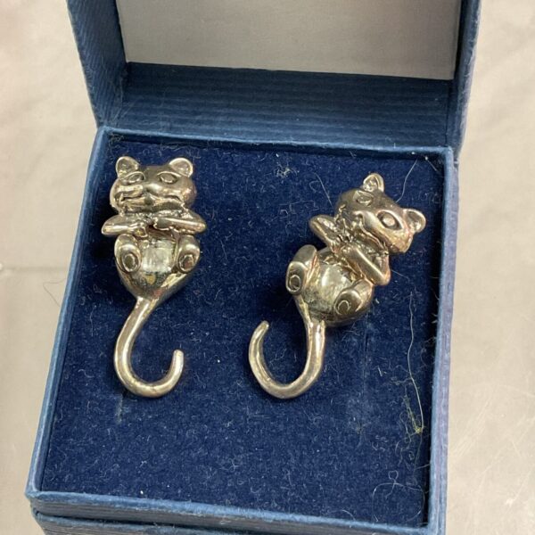 Close-up of silver articulated cat earrings on a display card.