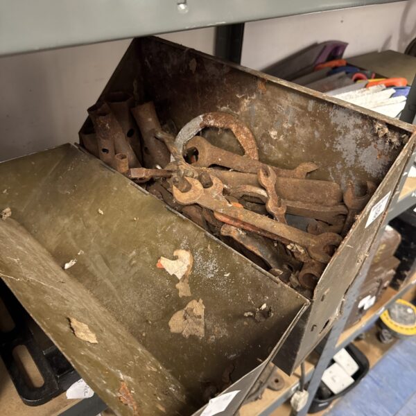 Vintage metal strongbox filled with rusty spanners.