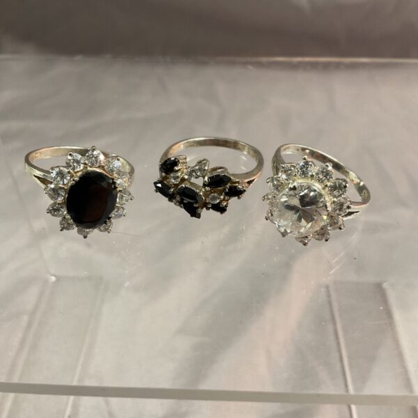 Lot of three silver stone set rings on display.