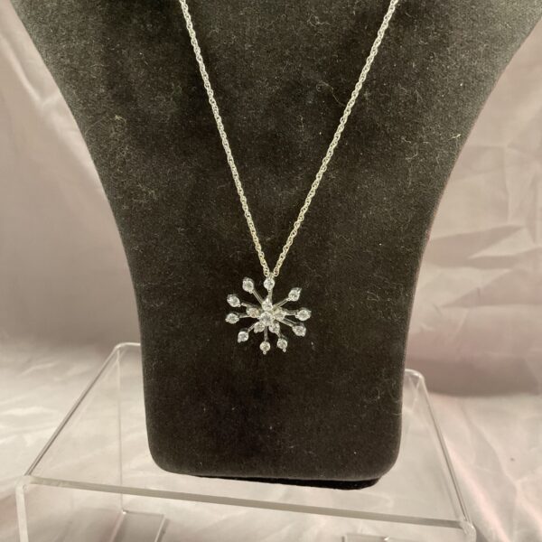Silver snowflake pendant necklace with white stone detail.