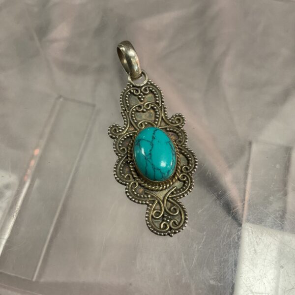 Vintage silver pendant with turquoise stone, detailed floral design.