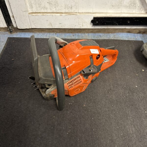 Vintage orange petrol chainsaw engine with black handle.