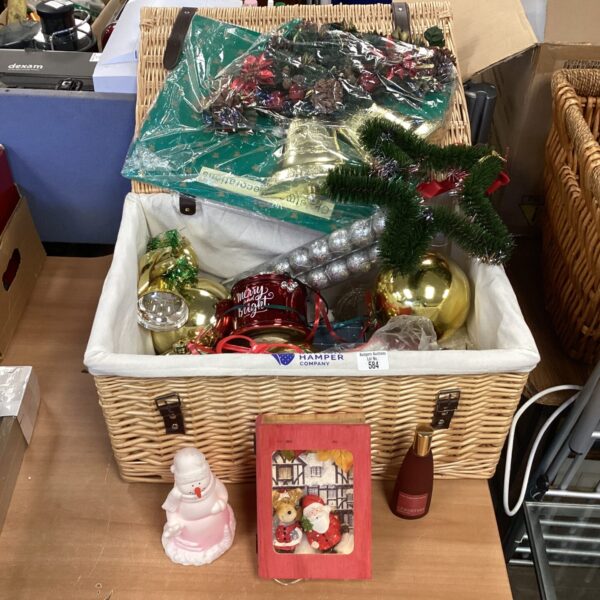 Wicker basket overflowing with assorted Christmas decorations and ornaments.