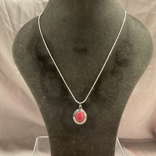 Silver necklace with a vibrant pink stone pendant on a snakelink chain.