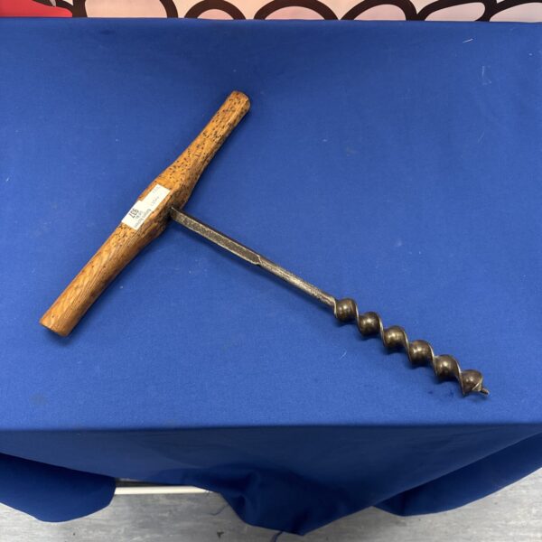 Vintage auger bit with wooden handle and twisted steel shaft.