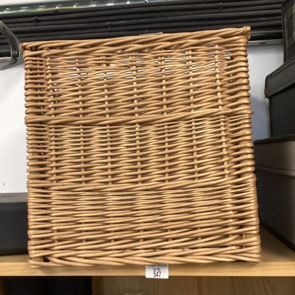 Rustic wicker log basket for storing firewood by the fireplace.