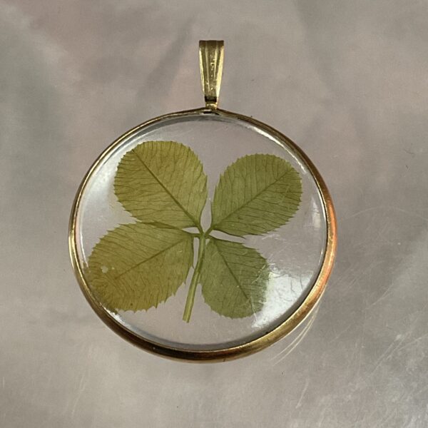 Close-up of a 9ct gold four leaf clover pendant.