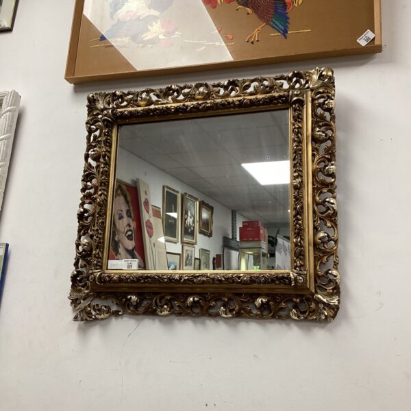 Ornate antique gilt framed mirror with floral carvings.