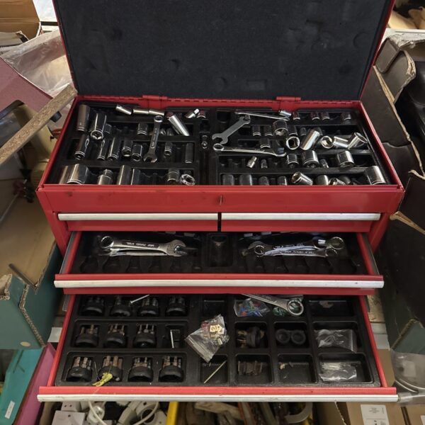 Red metal toolbox filled with various hand tools for workshop use.