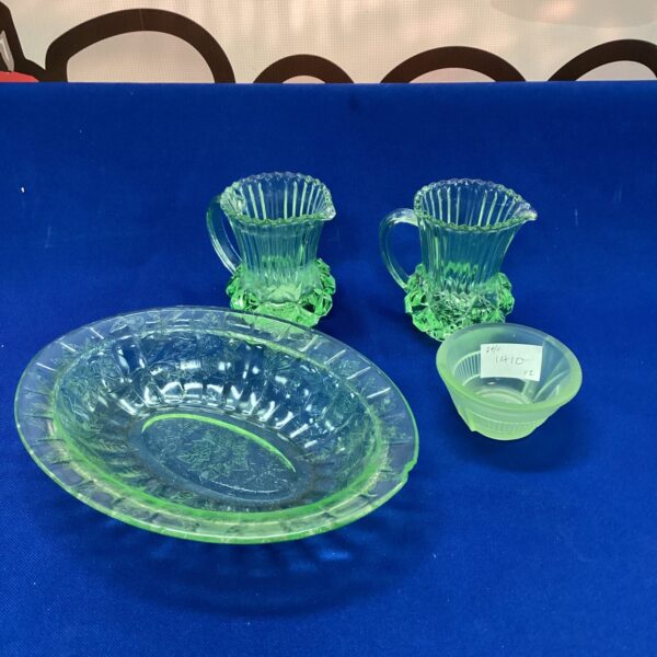 Vintage uranium glass collection with green creamer and decorative pieces.