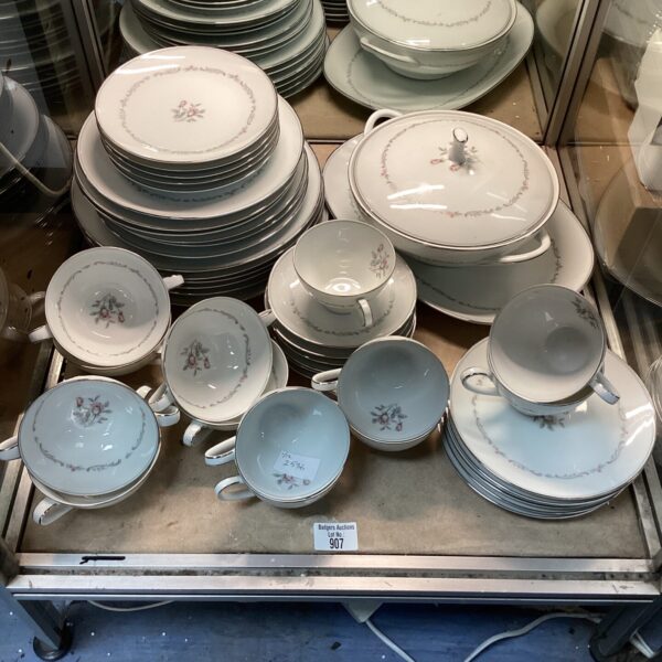 Stacked Noritake Mayfair dinner service pieces with floral design.