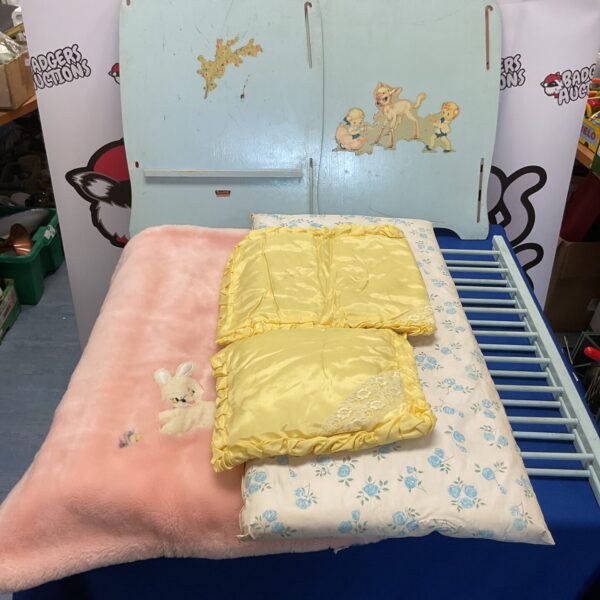 Vintage childs dolls cot with patterned bedding.