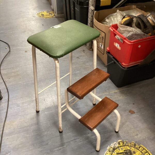 Vintage three-step metal stool with green top.