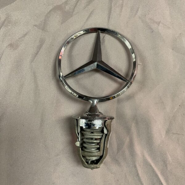 Vintage Mercedes Benz radiator mascot with three-pointed star emblem.
